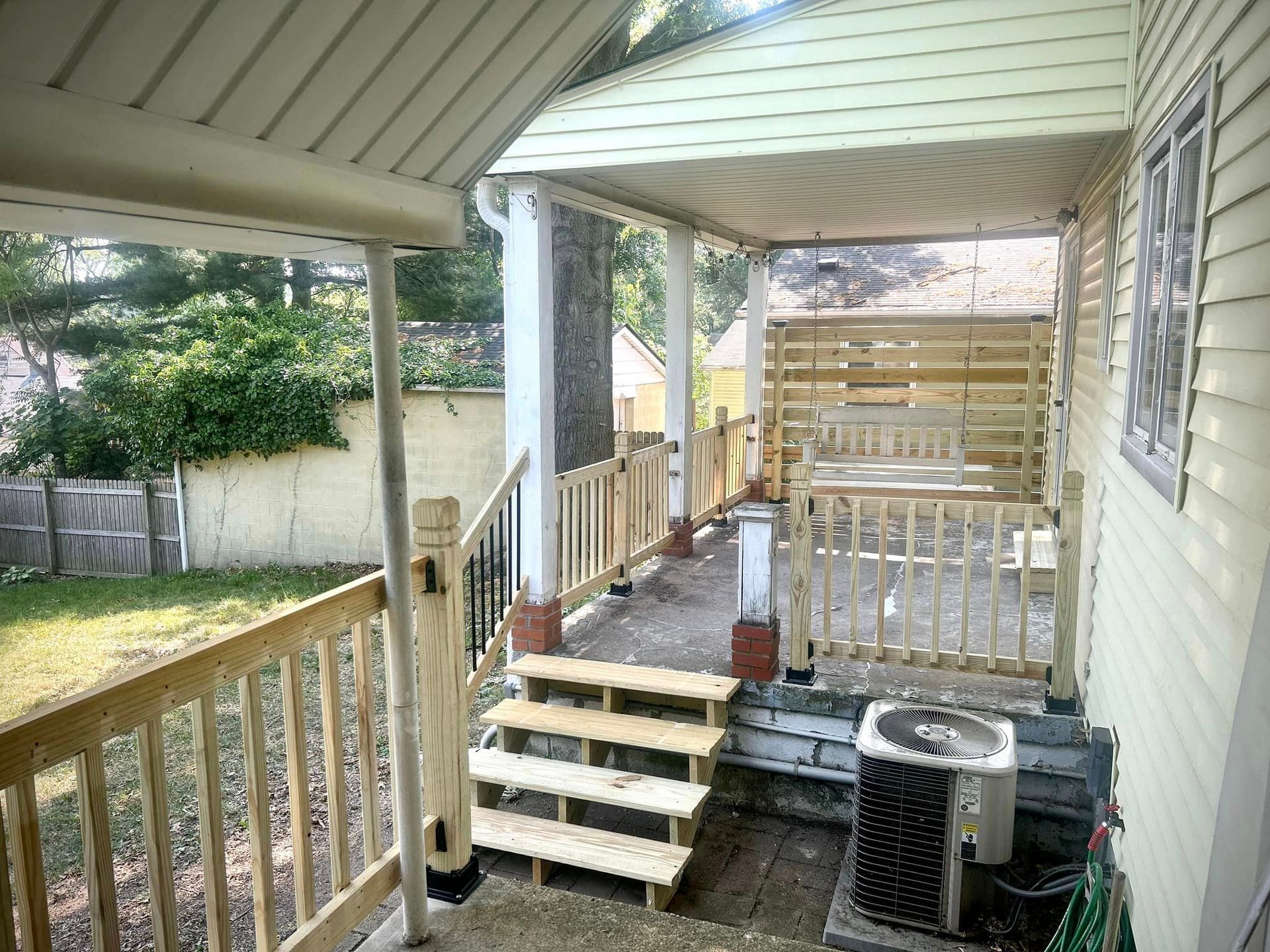 A porch with stairs leading up to it and an air conditioner.