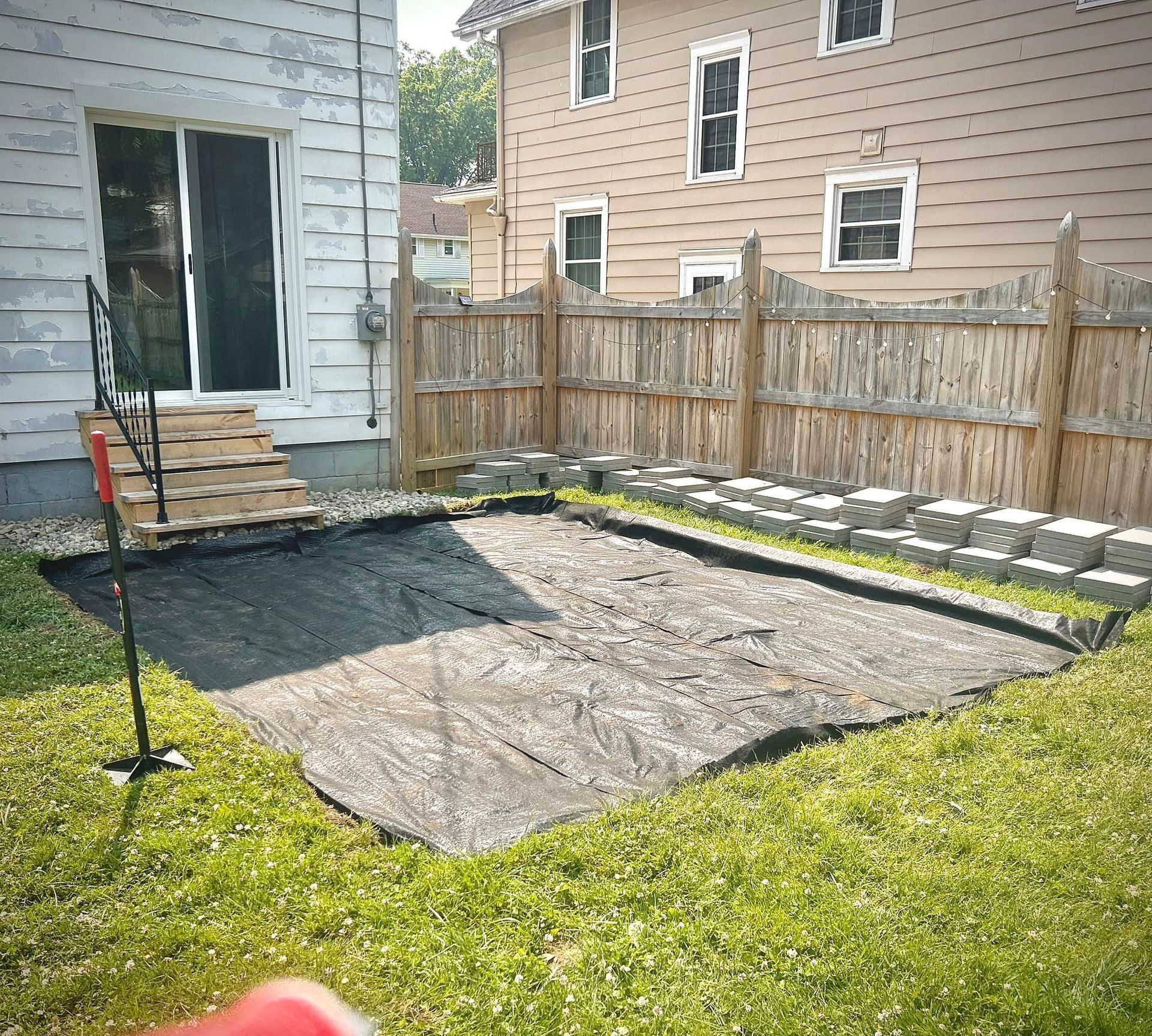 A backyard with a wooden fence and a large tarp in the middle of it.