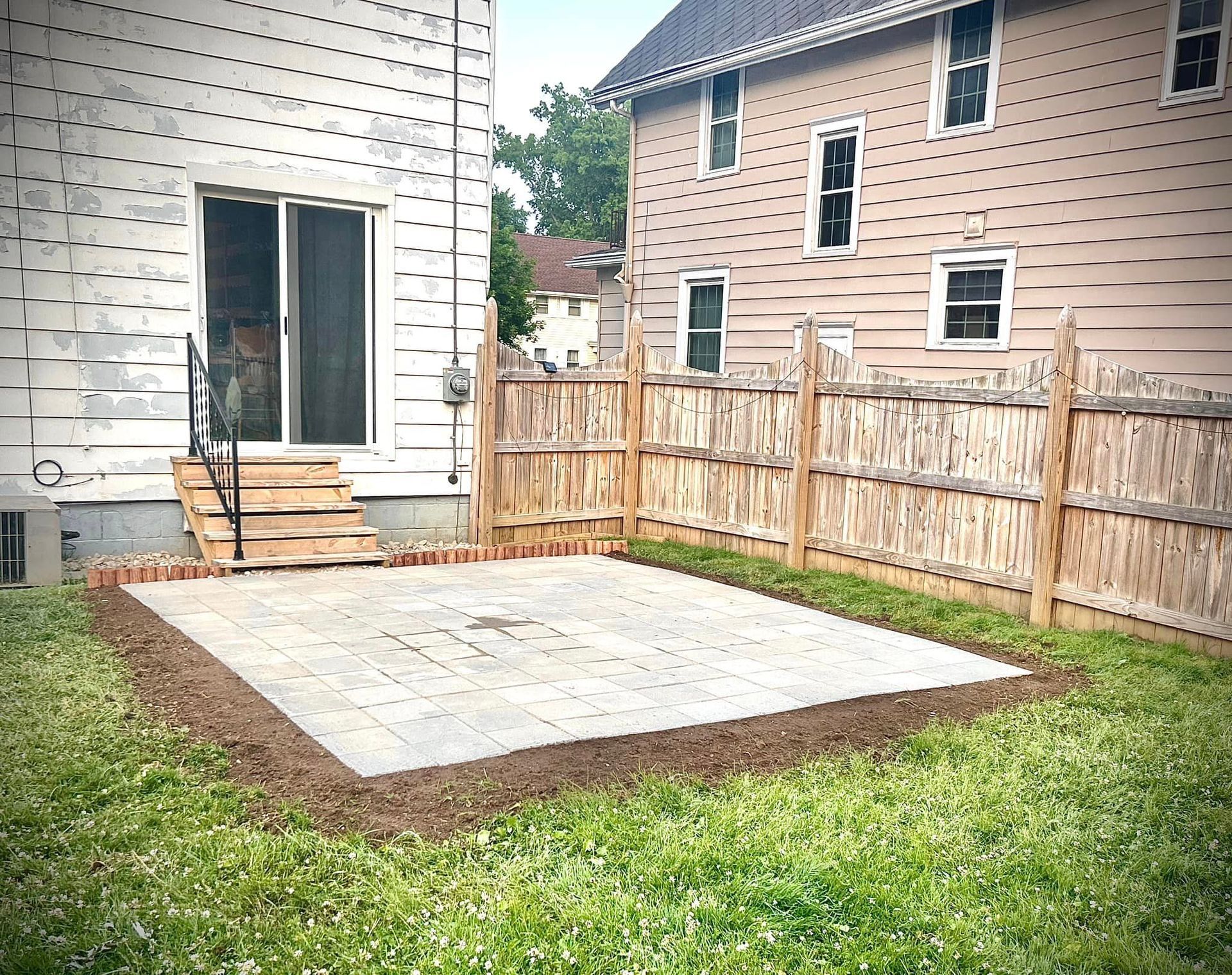 A backyard with a concrete patio and a wooden fence.