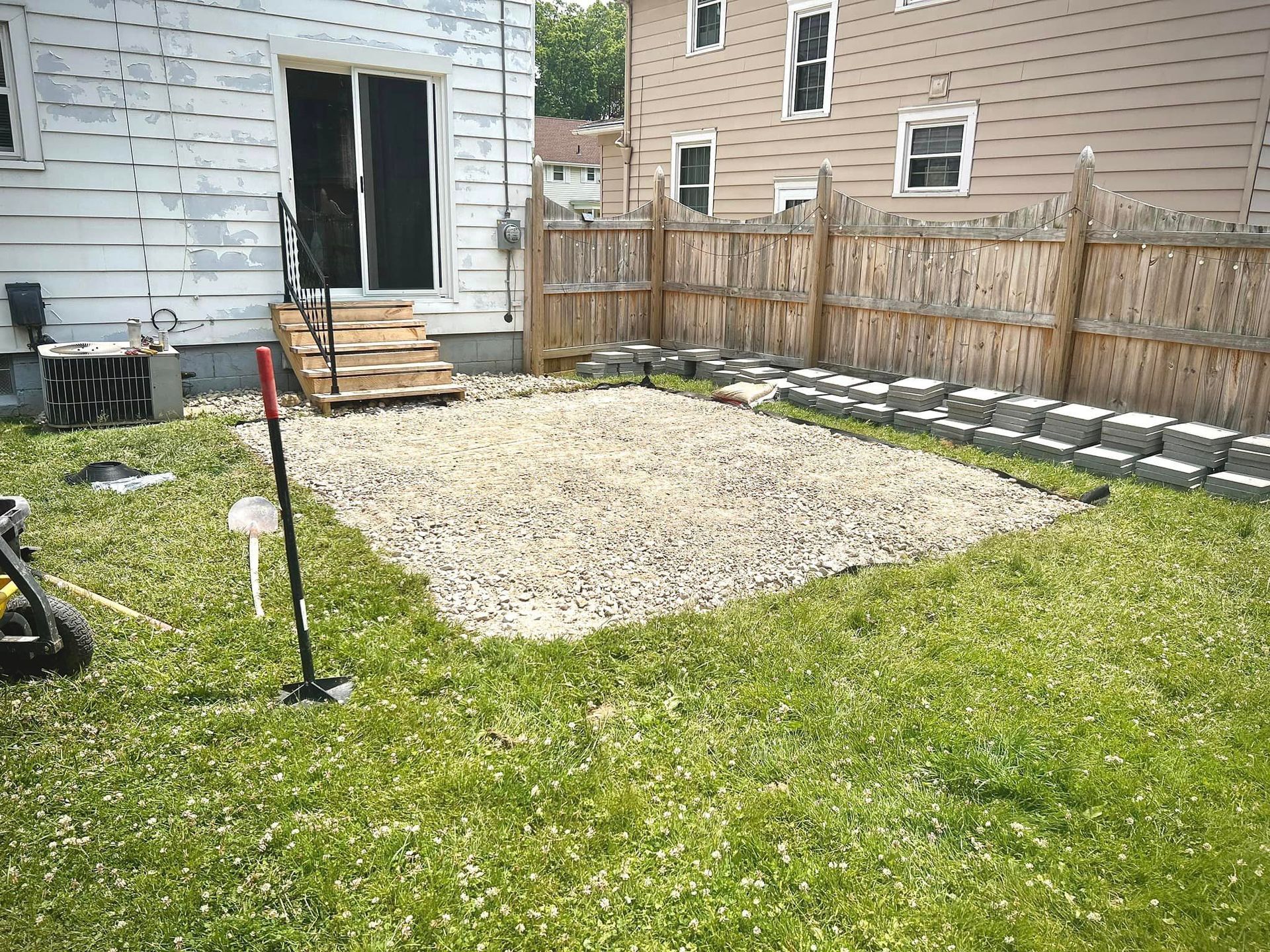 A backyard with a lot of grass and a fence in front of a house.