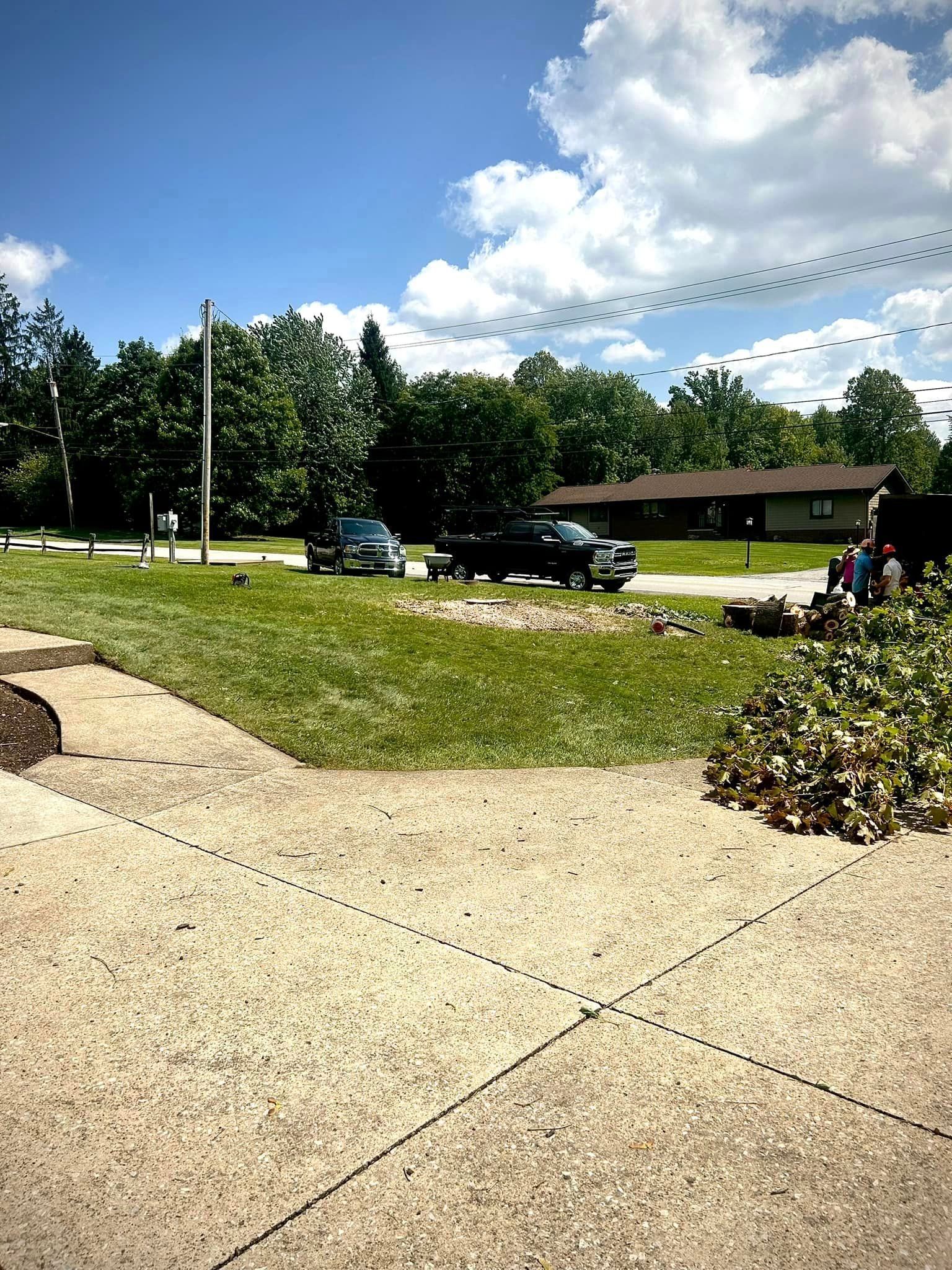 A concrete walkway leading to a grassy field with a house in the background.