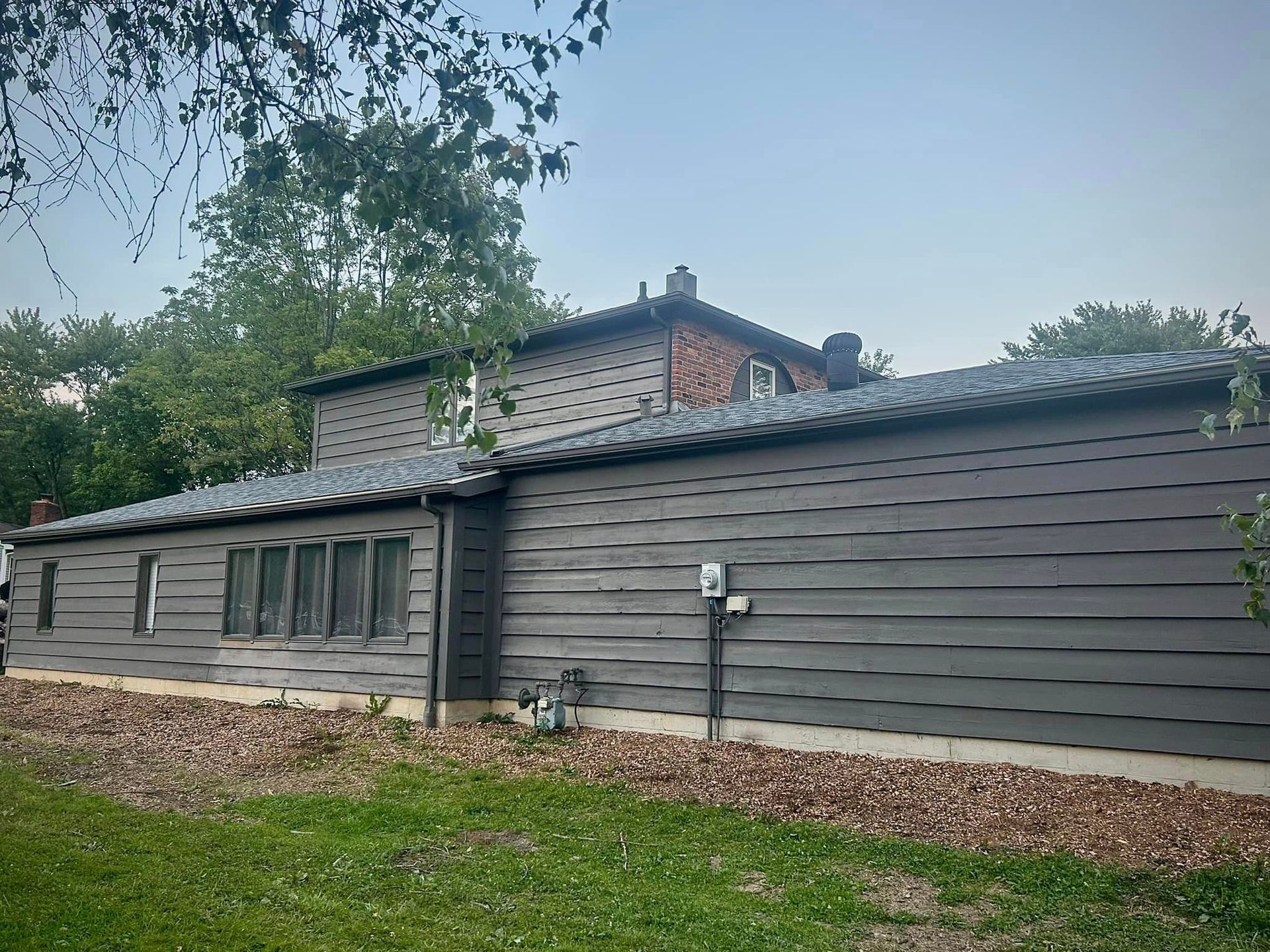 A large house with a gray siding and a blue roof