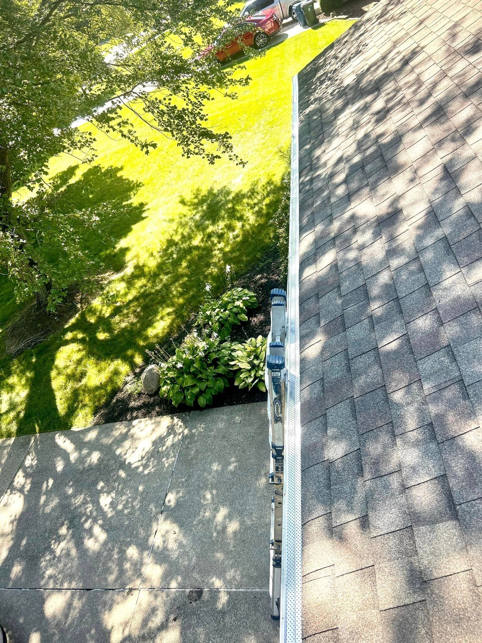 A roof with a gutter on it and trees in the background.