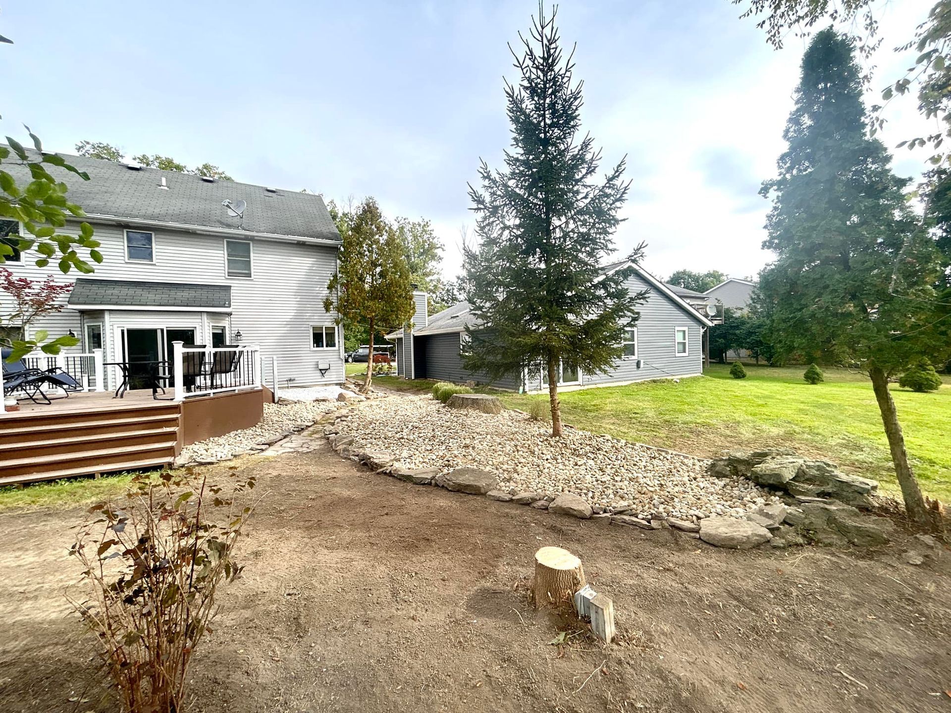 The backyard of a house with a stump in the middle of it.