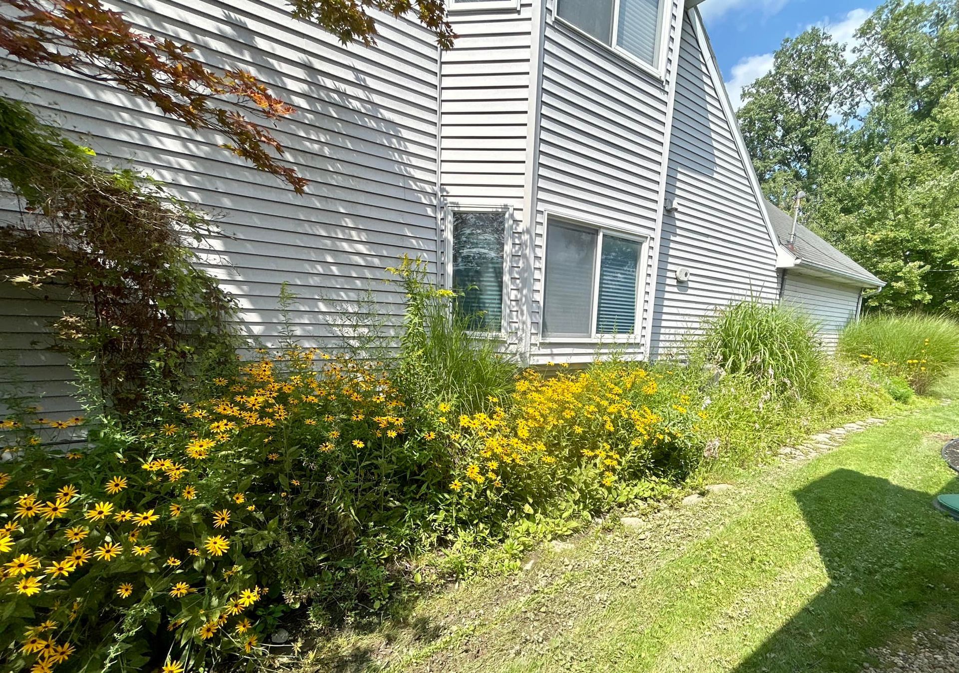 A white house with a lot of flowers in front of it.