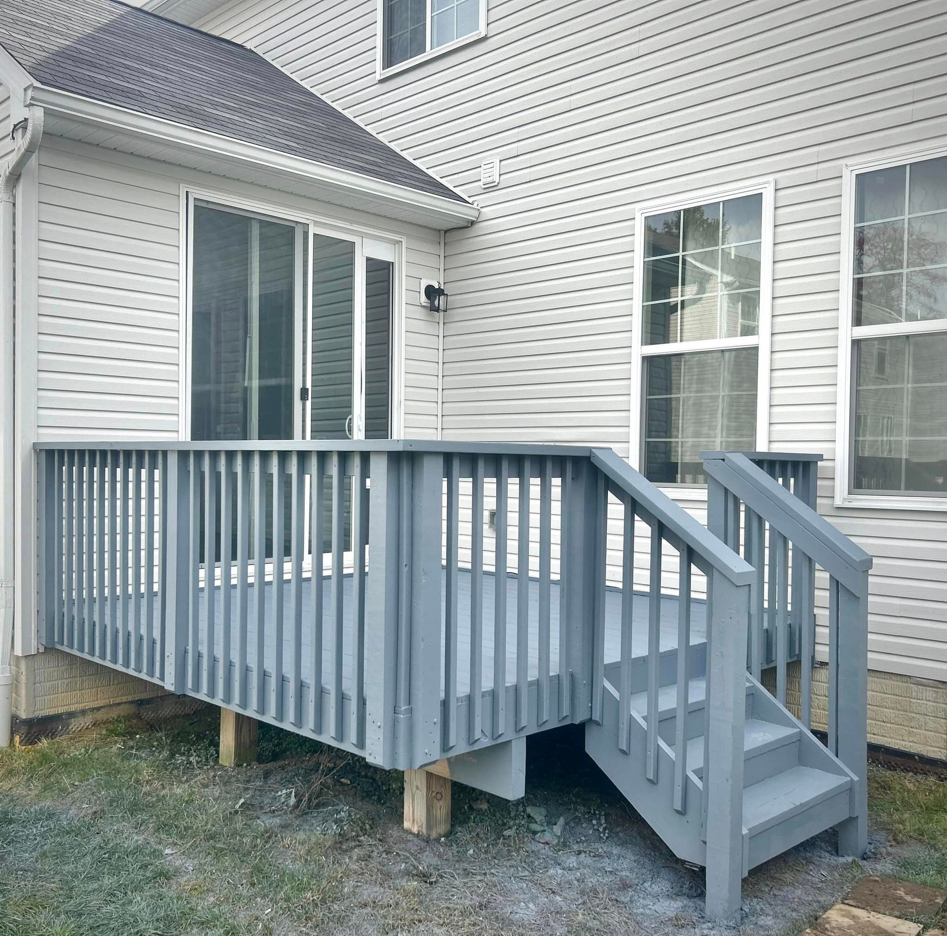 A white house with a gray deck and stairs