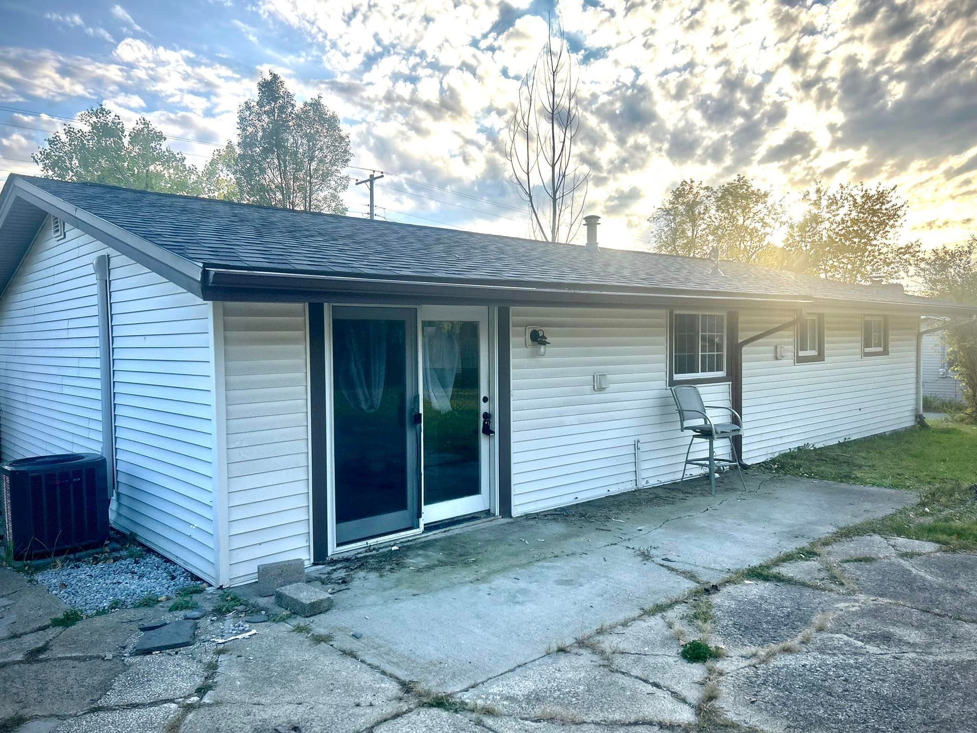 A white house with a black roof and a sliding glass door.