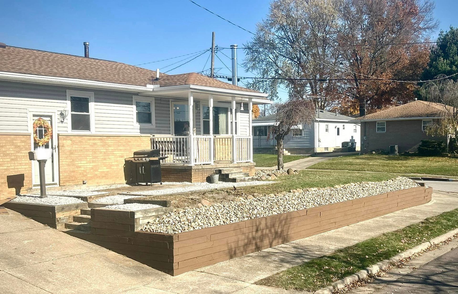 A house with a porch and a brick wall in front of it.