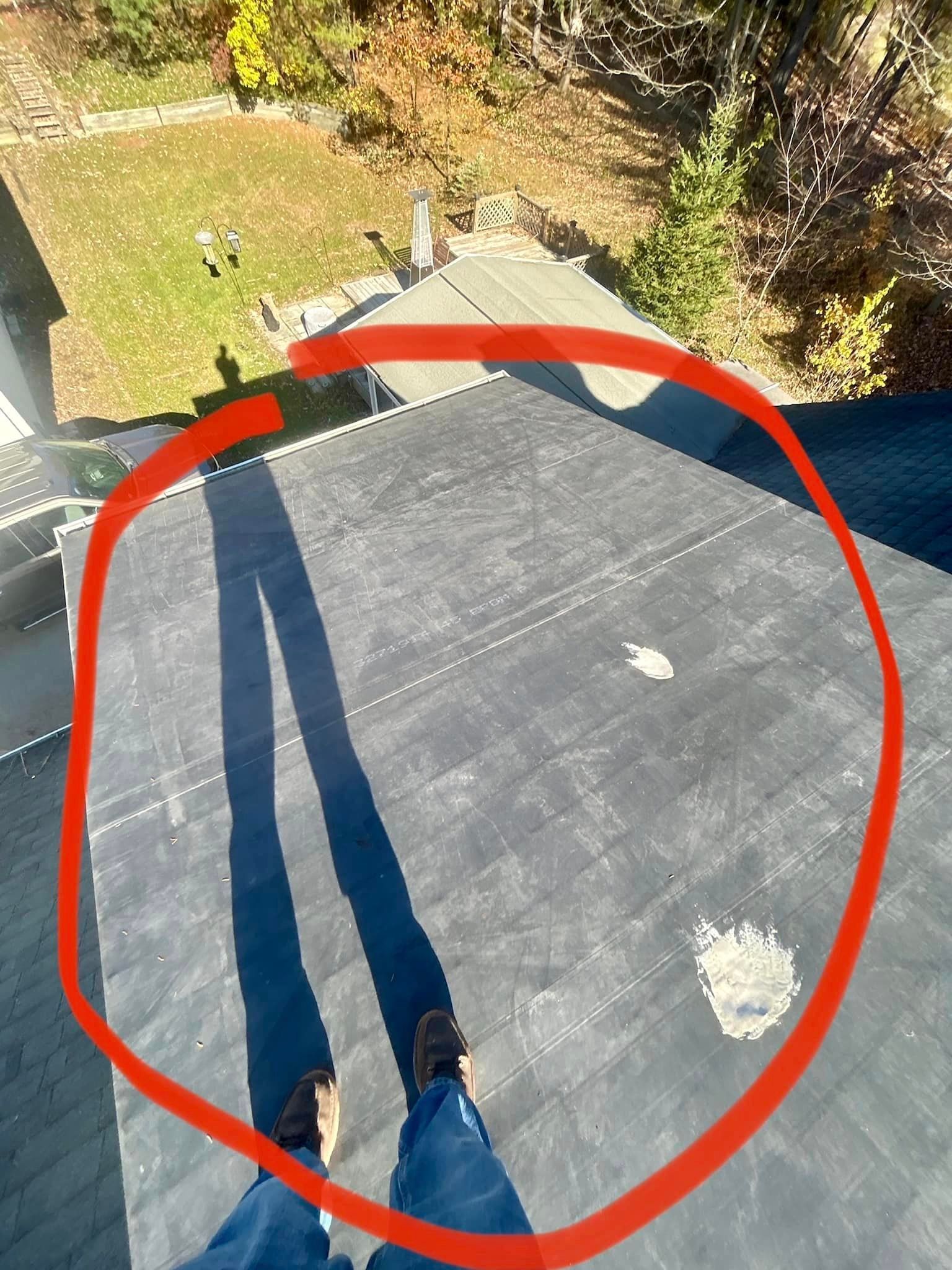 A person is standing on top of a roof with a red circle around their feet.