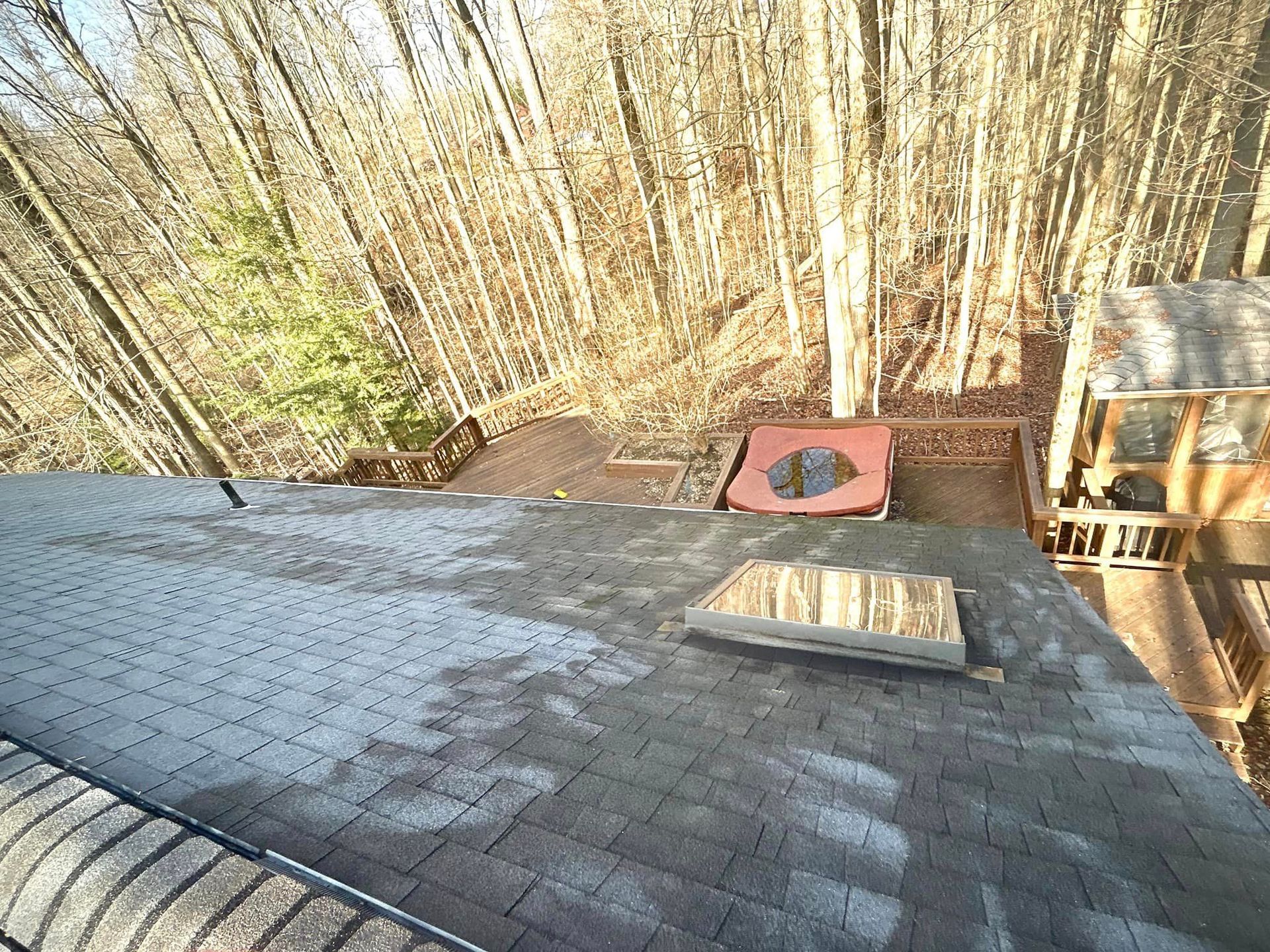 An aerial view of a roof with a chimney and trees in the background.