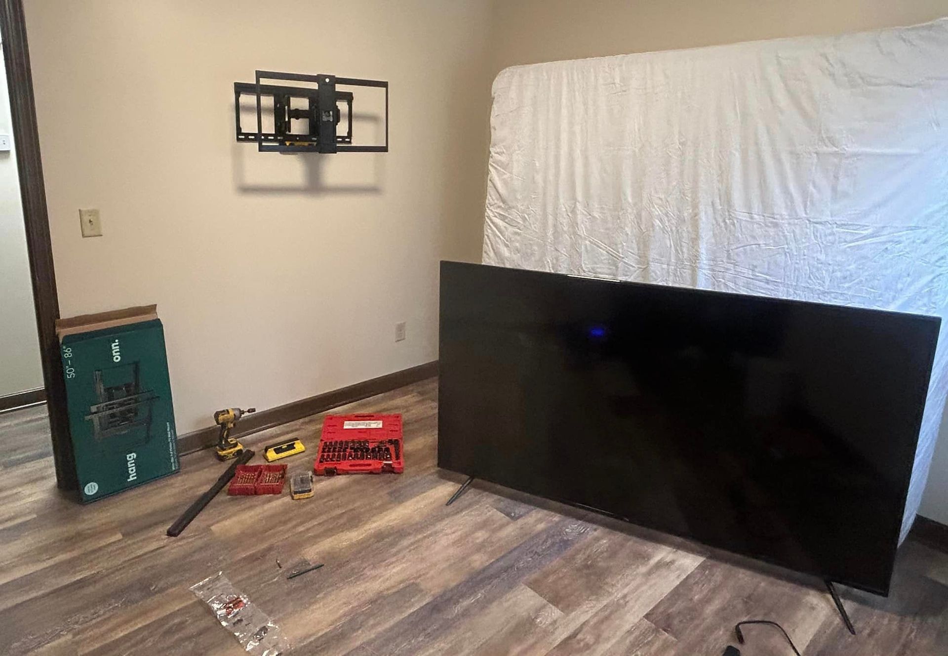 A large flat screen tv is sitting on a wooden floor in a living room.