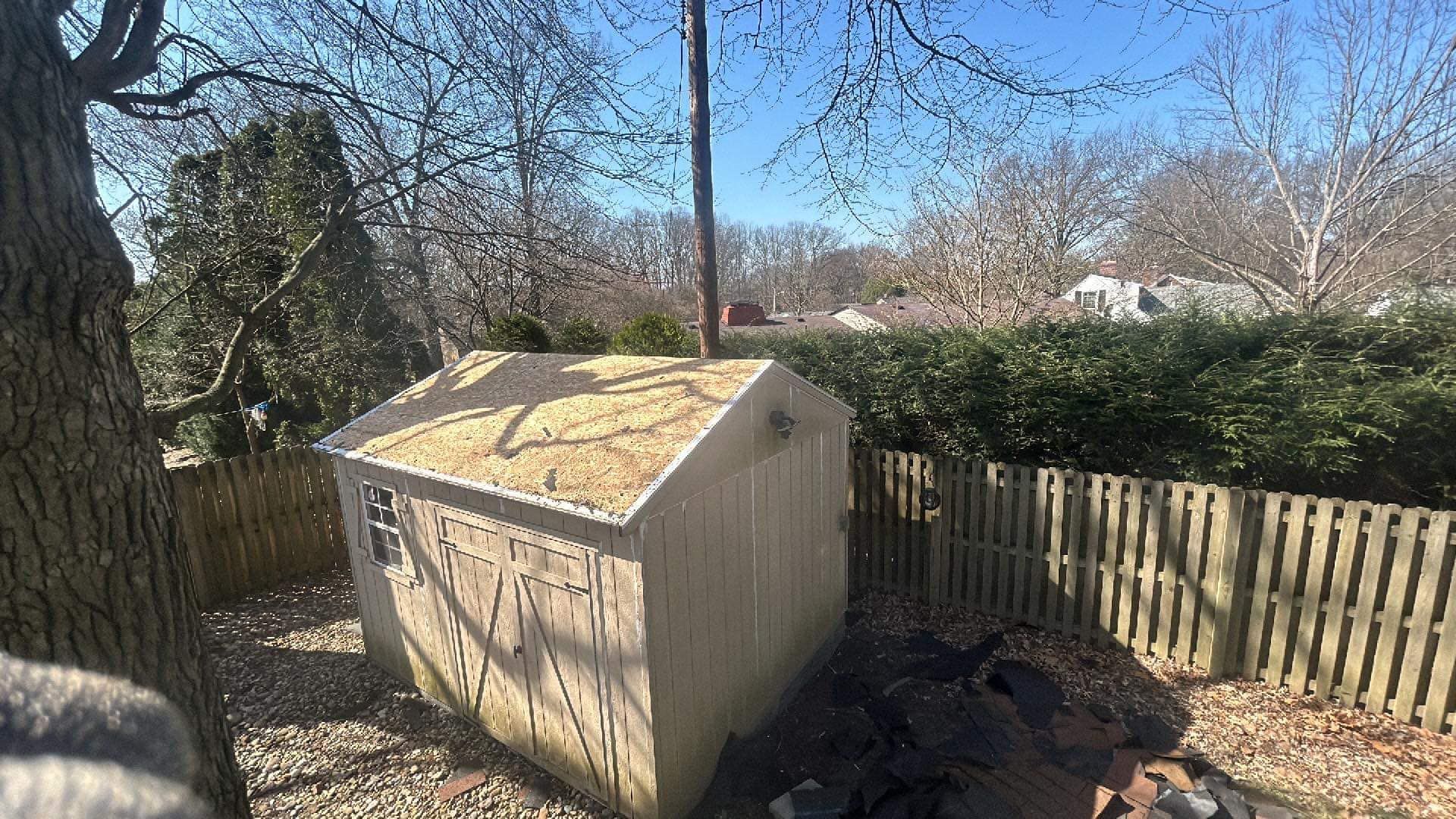 A shed in a backyard with a wooden fence and trees in the background.