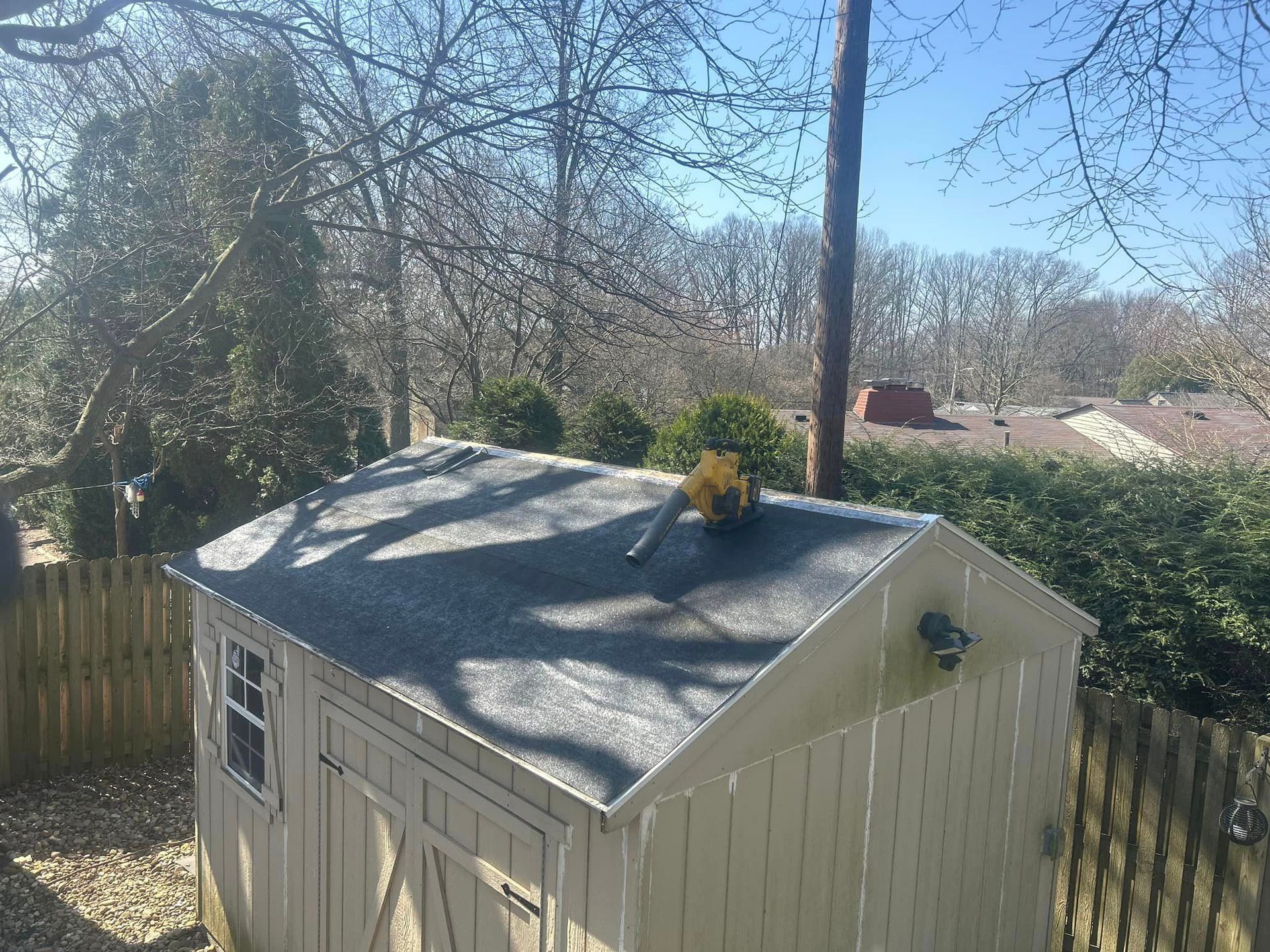 A person is working on the roof of a shed.
