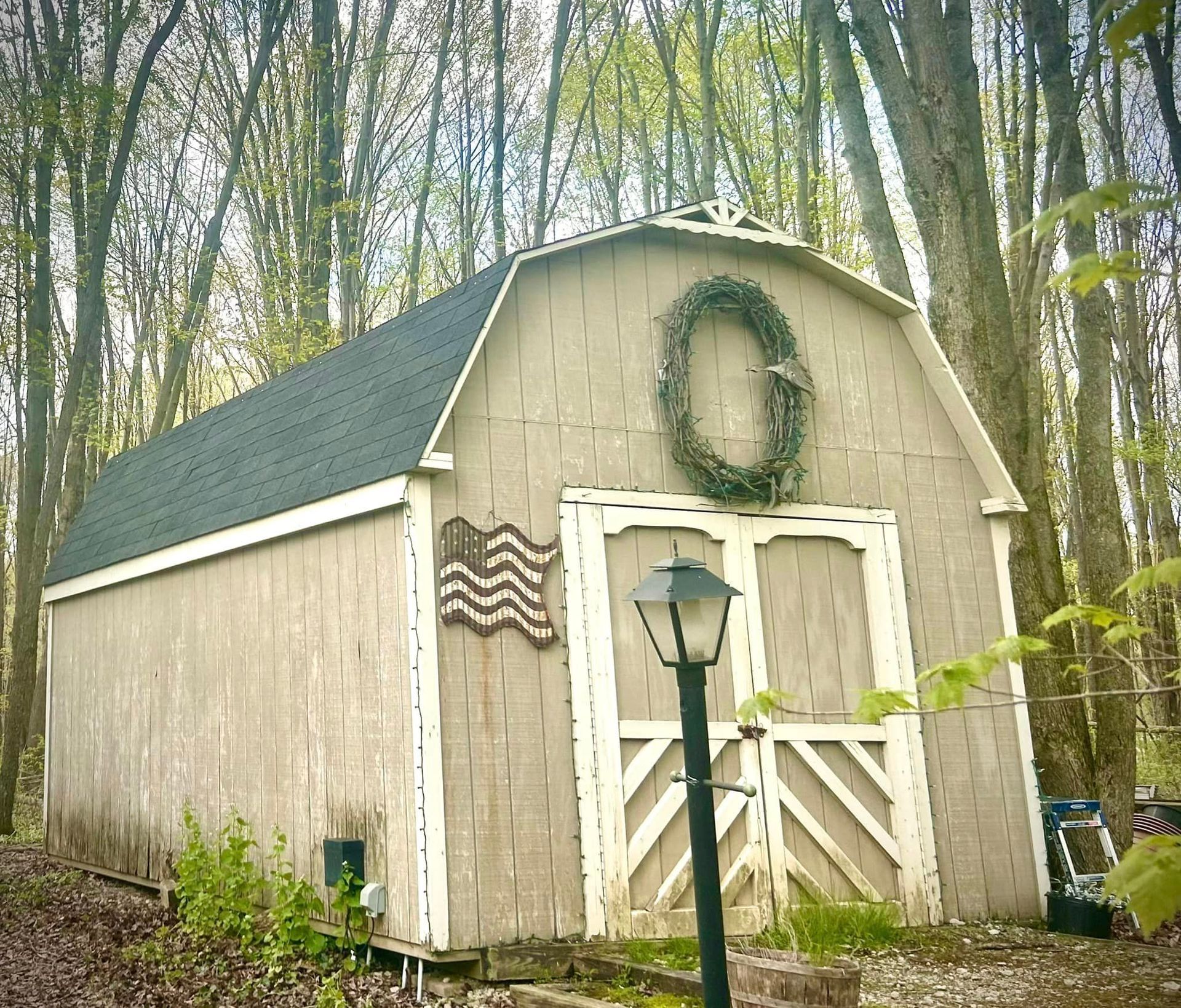 A barn with a wreath on the roof is surrounded by trees
