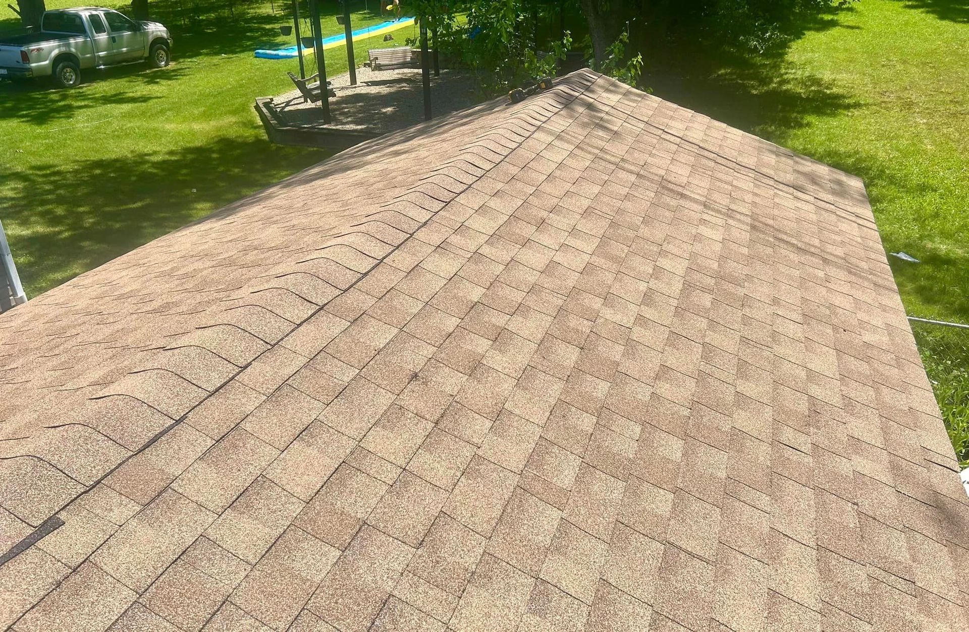 A roof with a lot of shingles on it is sitting on top of a lush green field.
