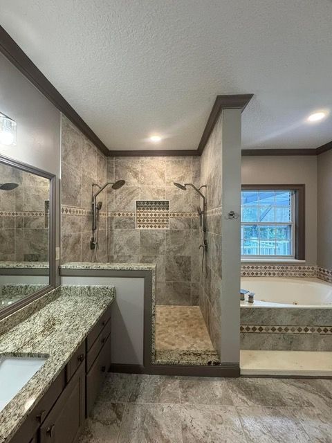 Bathroom with large shower, dual shower heads, tile walls, and a tub by a window.