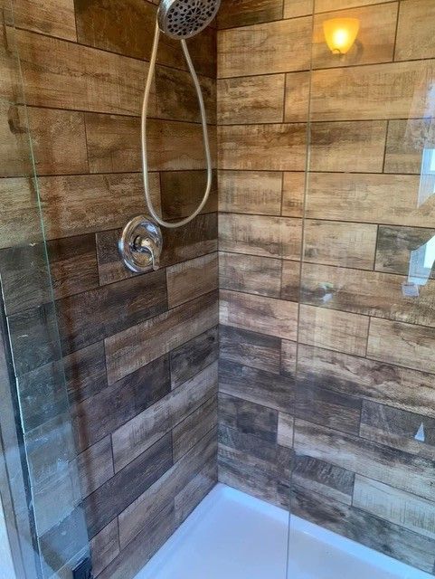 Shower with wood-look tile, glass door, and chrome fixtures.