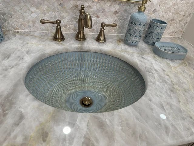 Blue patterned bathroom sink with bronze fixtures on a light-colored countertop.