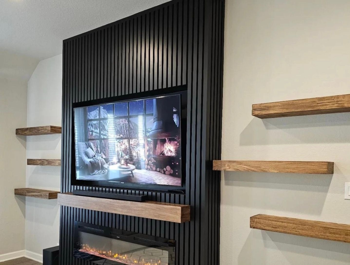 Black slatted wall with a TV and fireplace. Wooden shelves on the sides. Beige walls.