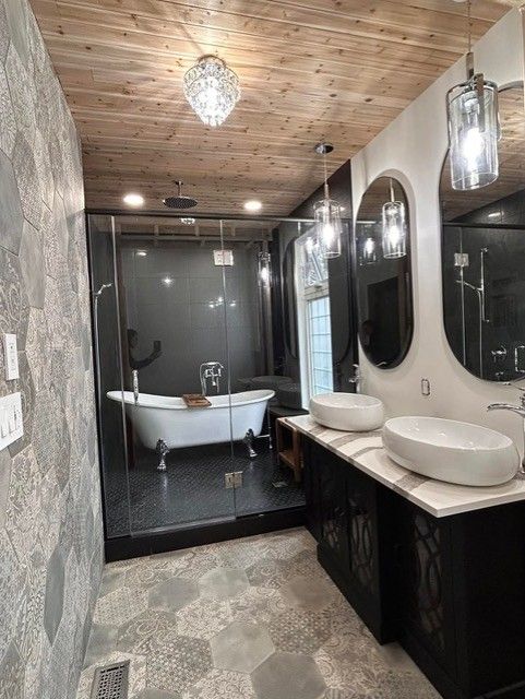 Modern bathroom with clawfoot tub, glass shower, double sinks, wood ceiling, gray walls.