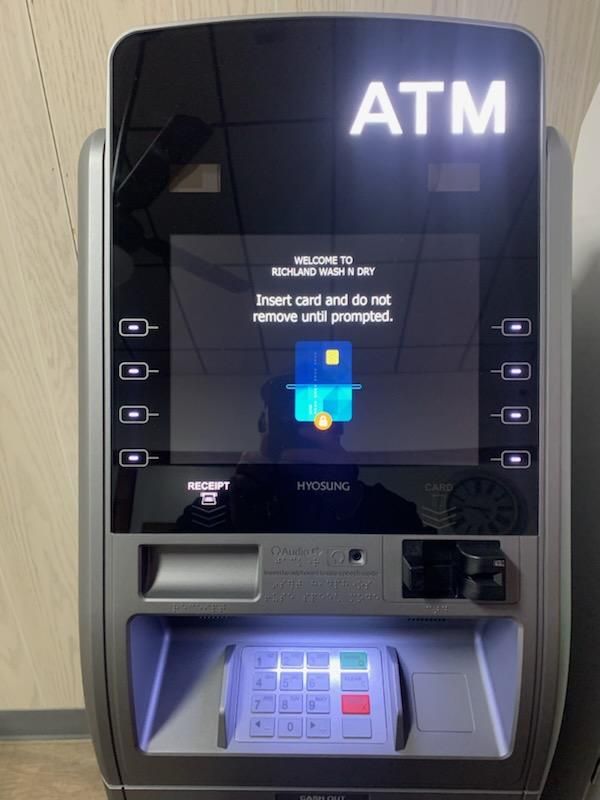 Row of commercial washing machines in a laundromat, cream-colored with large, circular doors.
