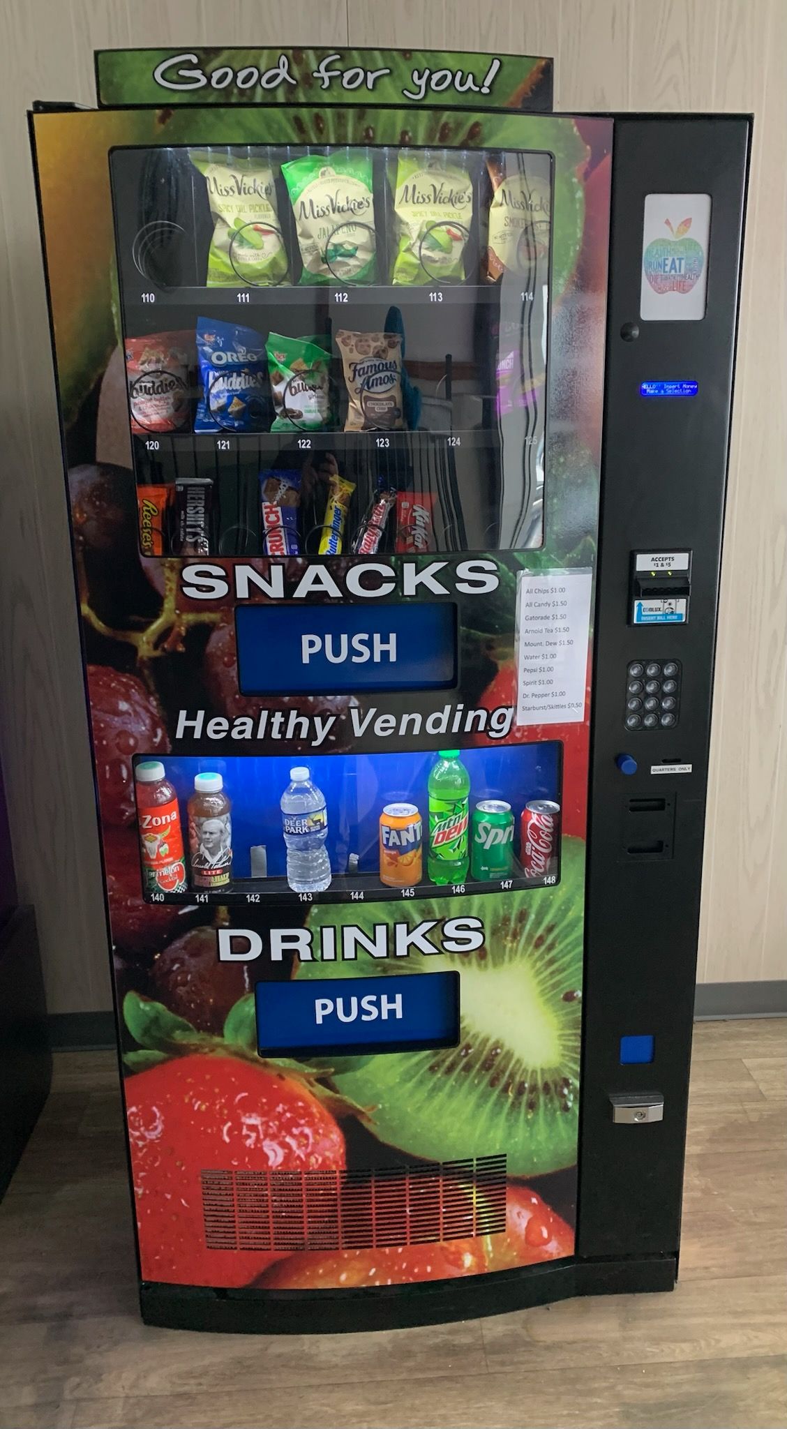 Person loads laundry from green basket into a commercial dryer at a laundromat.