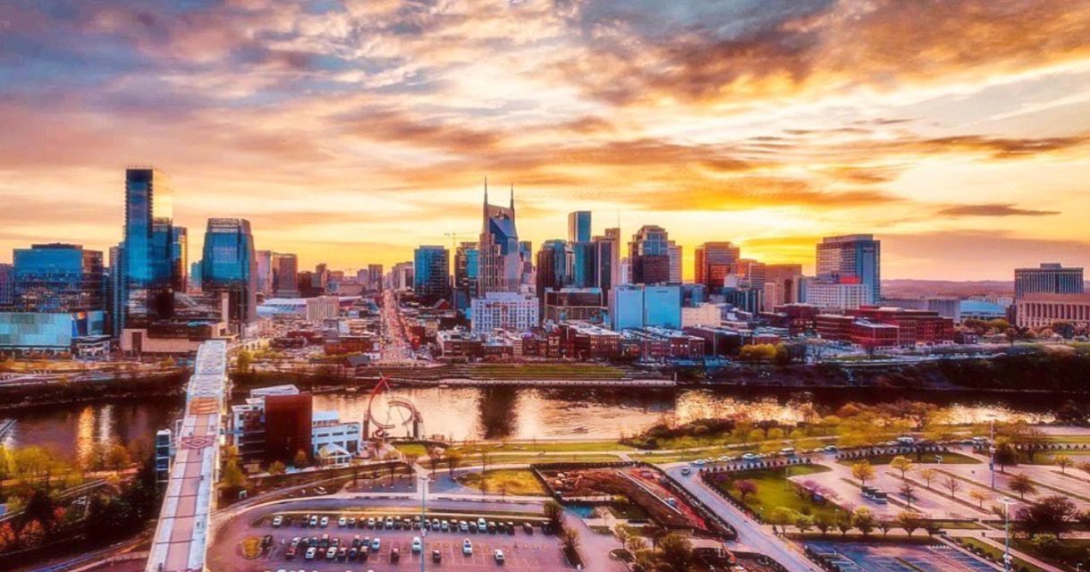 Nashville skyline at sunset with colorful sky over the river.