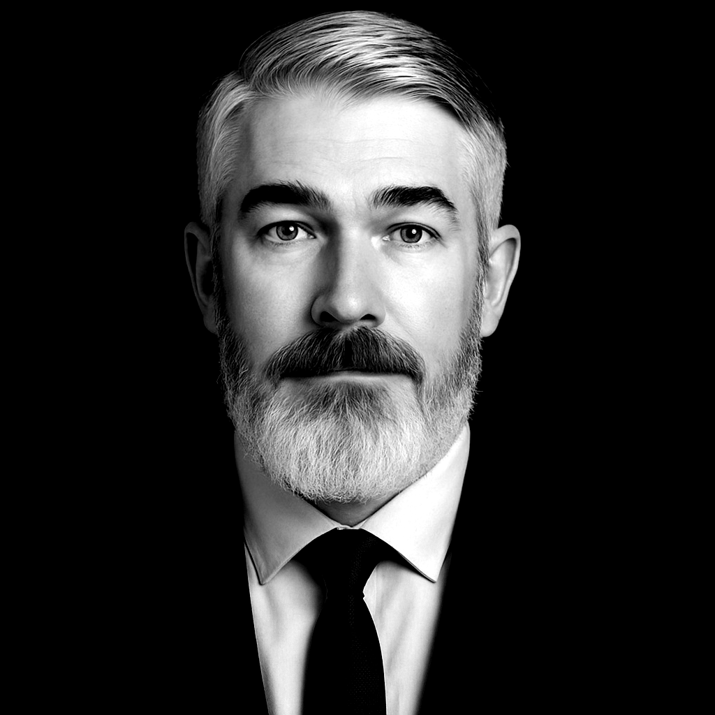 A man with a beard is looking at the camera in a black and white photo.