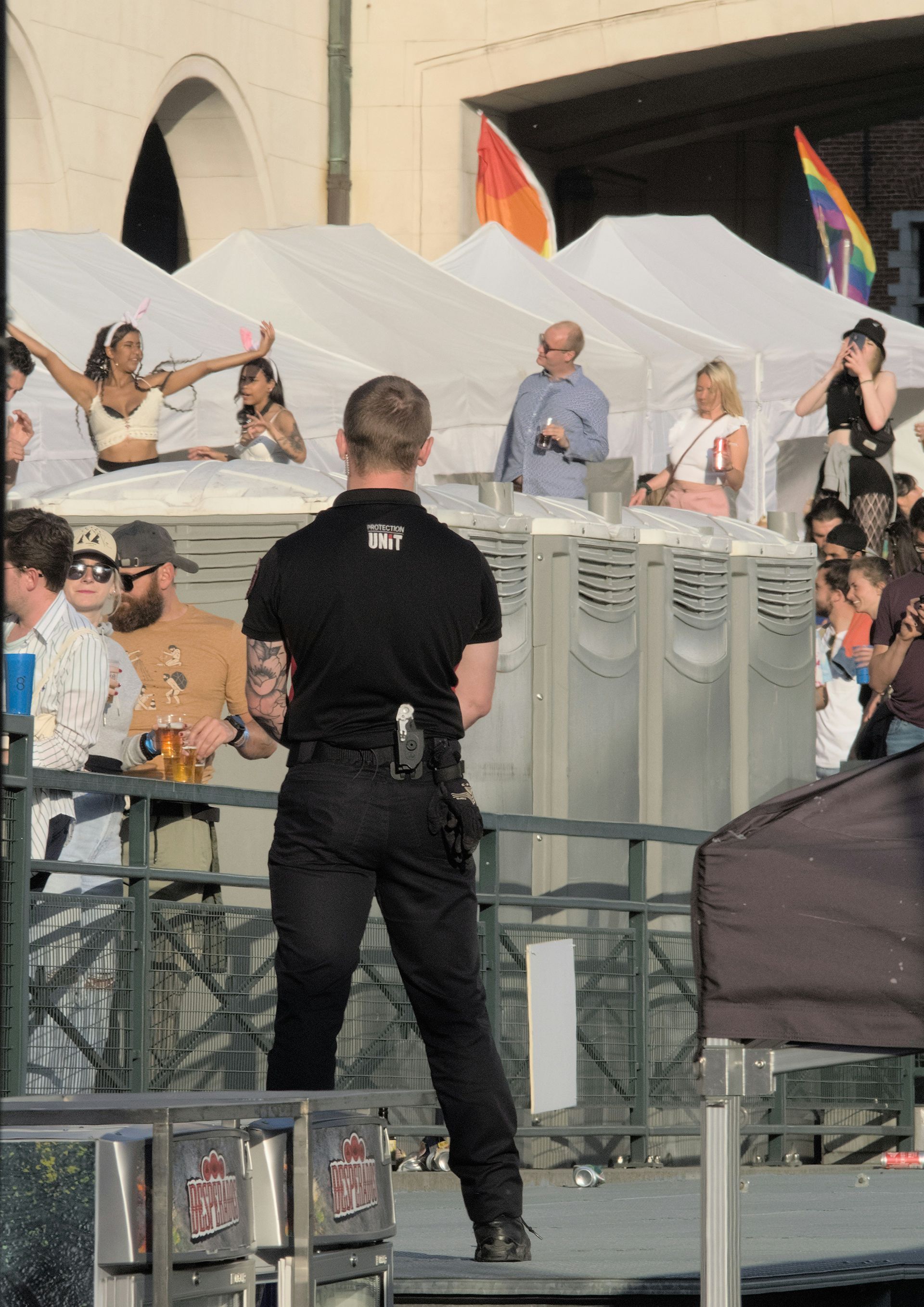 A man standing in front of a crowd with a rainbow flag in the background