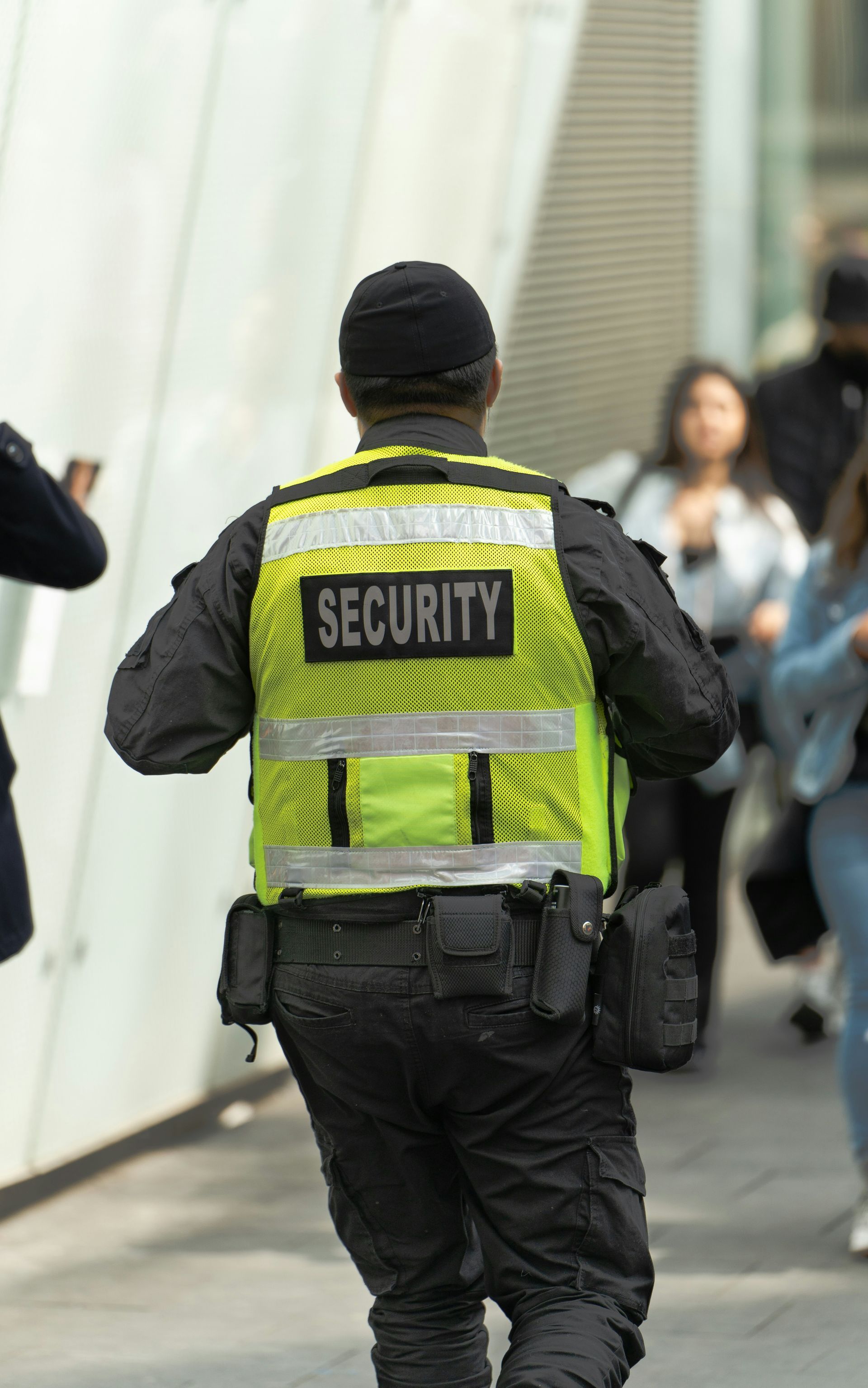 A security guard wearing a yellow vest with the word security on it