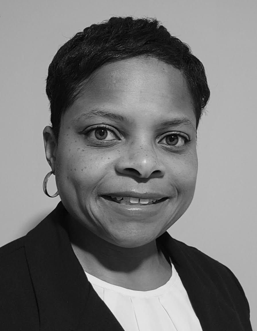 Woman with short hair wearing a dark jacket, white top, and hoop earrings smiles.