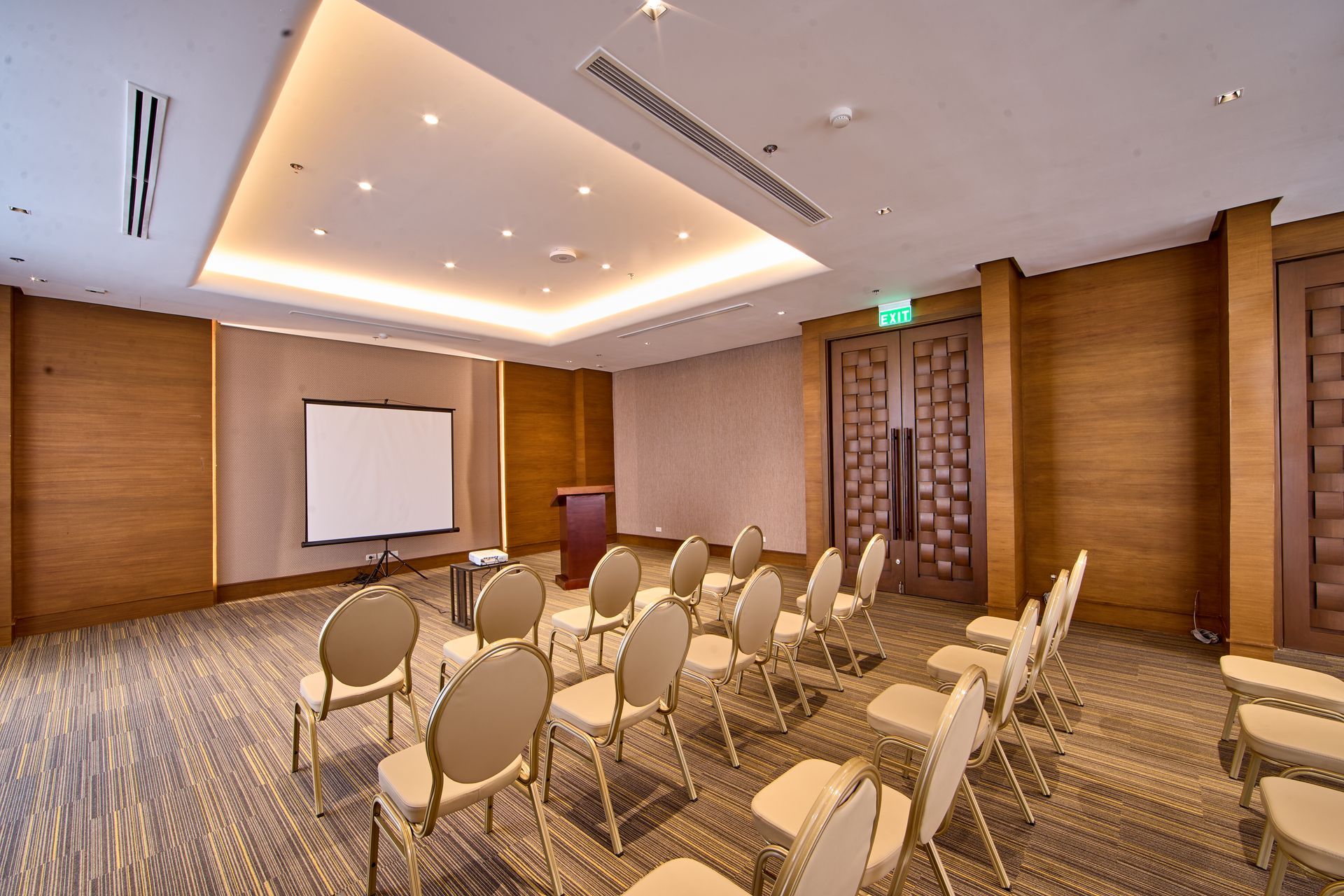 Conference room with chairs, projector screen, podium, and wood paneling.