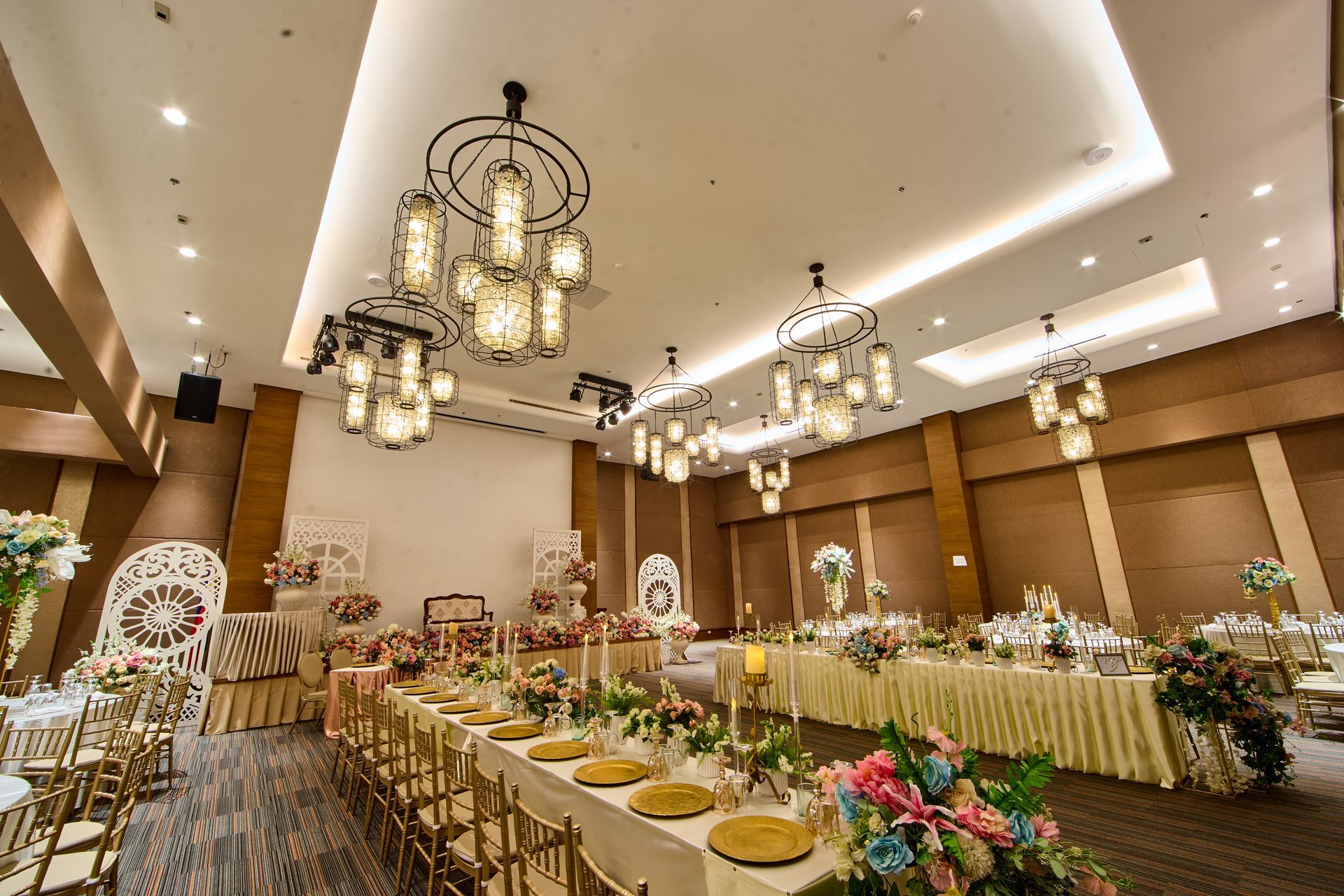 Elegant ballroom set up for an event. Tables with centerpieces and decorative lighting.