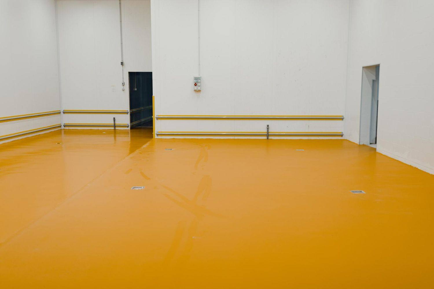 A large empty room with a yellow floor and white walls.