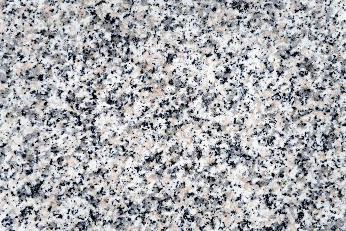 A close up of a white granite counter top with black spots.