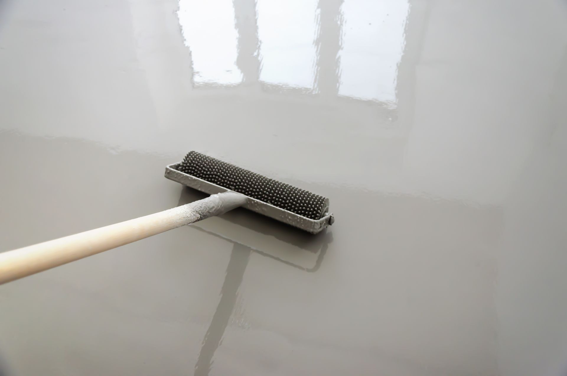 A person is painting a floor with a roller.