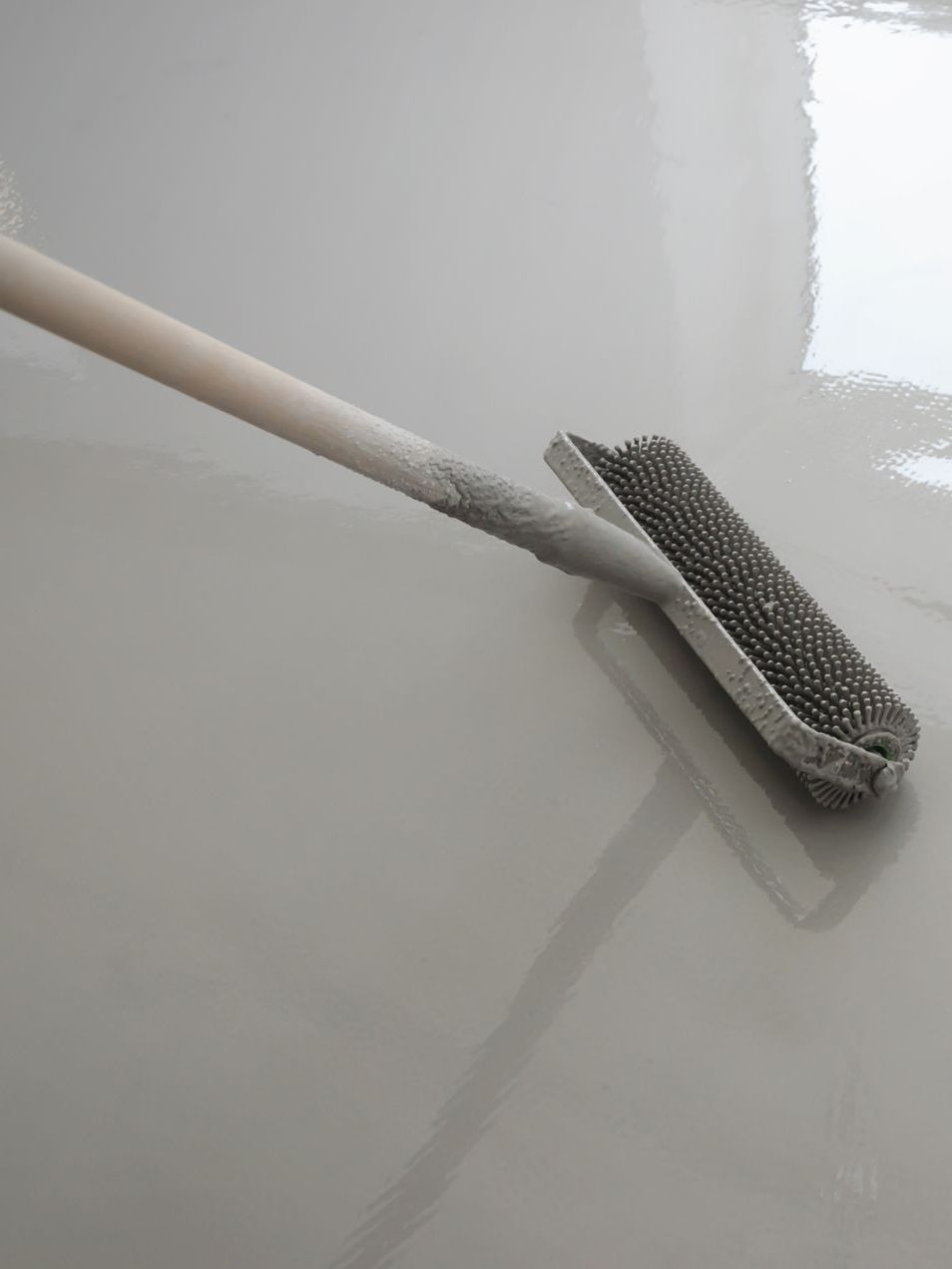 A wire brush is being used to paint a floor.