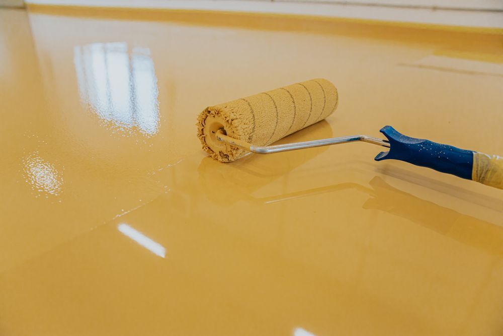 A person is painting a floor with a roller.