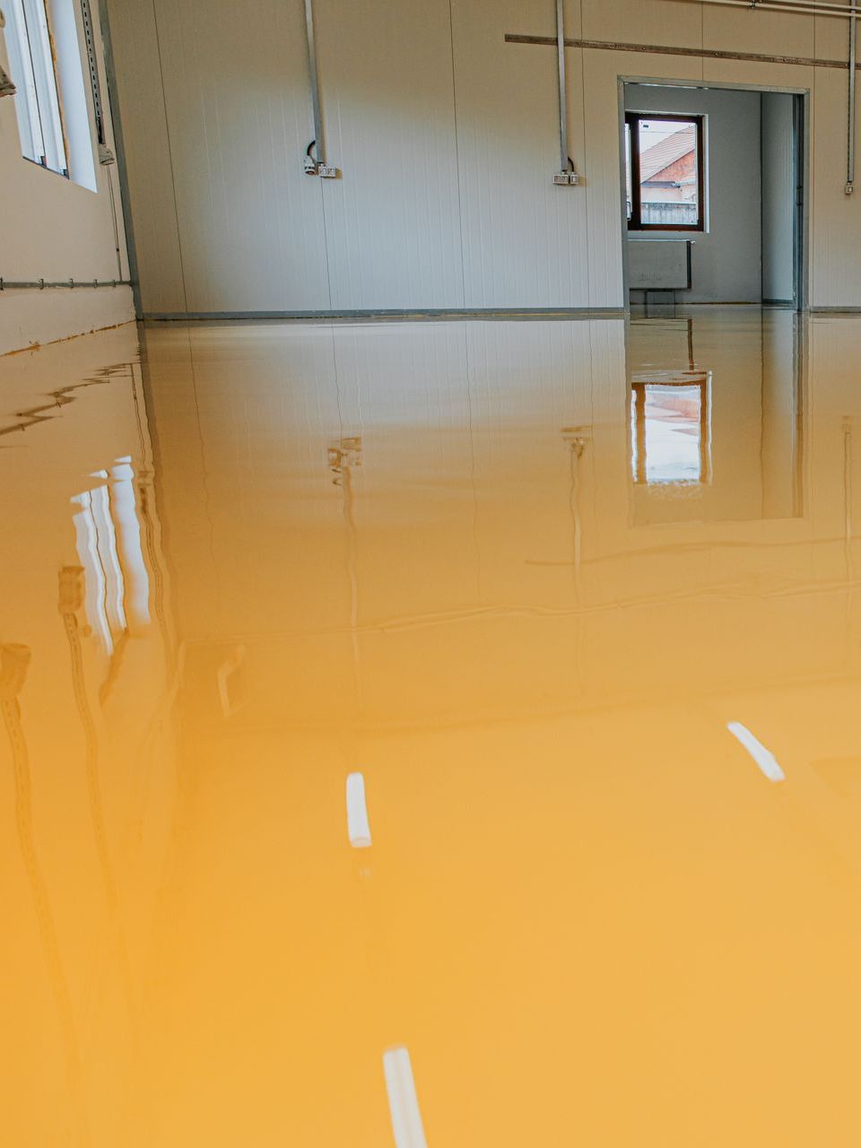 A large room with a yellow floor and a window.