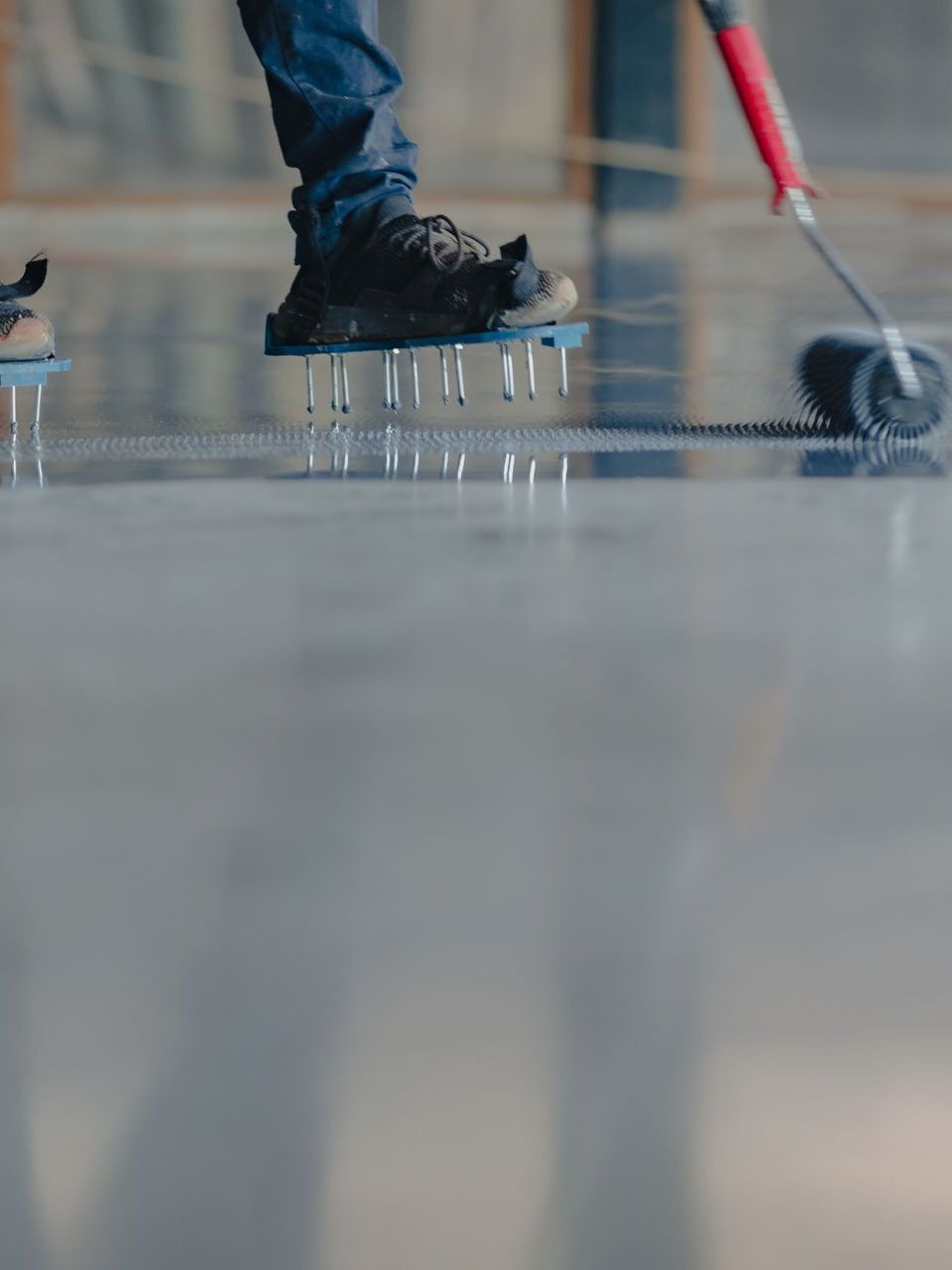 A person is painting a concrete floor with a roller.