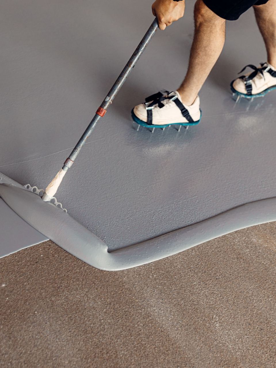 A person is painting a floor with a mop