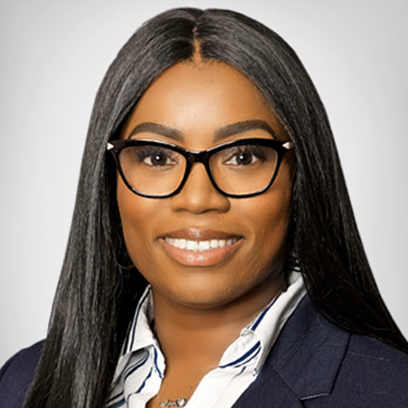 A woman wearing glasses and a suit is smiling for the camera.