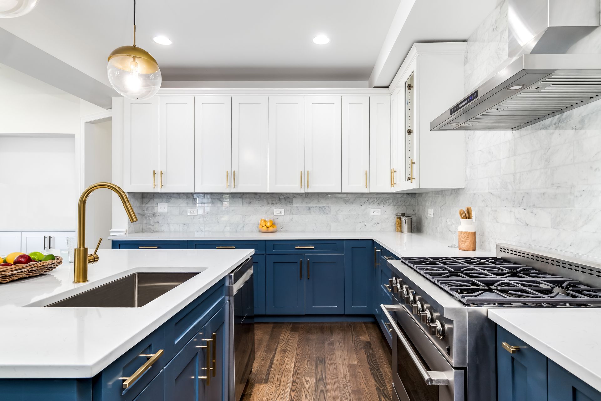 Dark blue and white cabinets and a wood range hood in a kitchen.