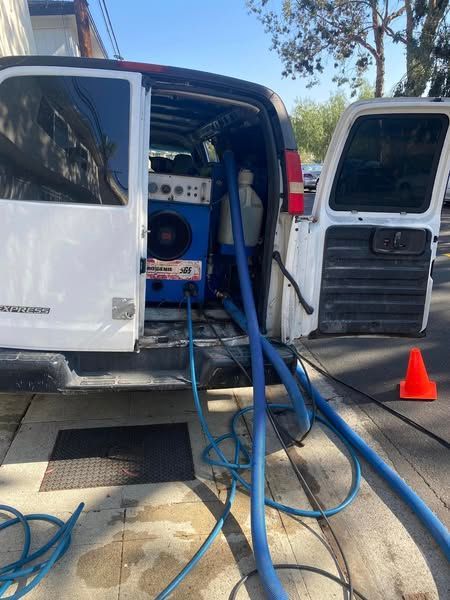 A white van is parked on the side of the road with the door open.