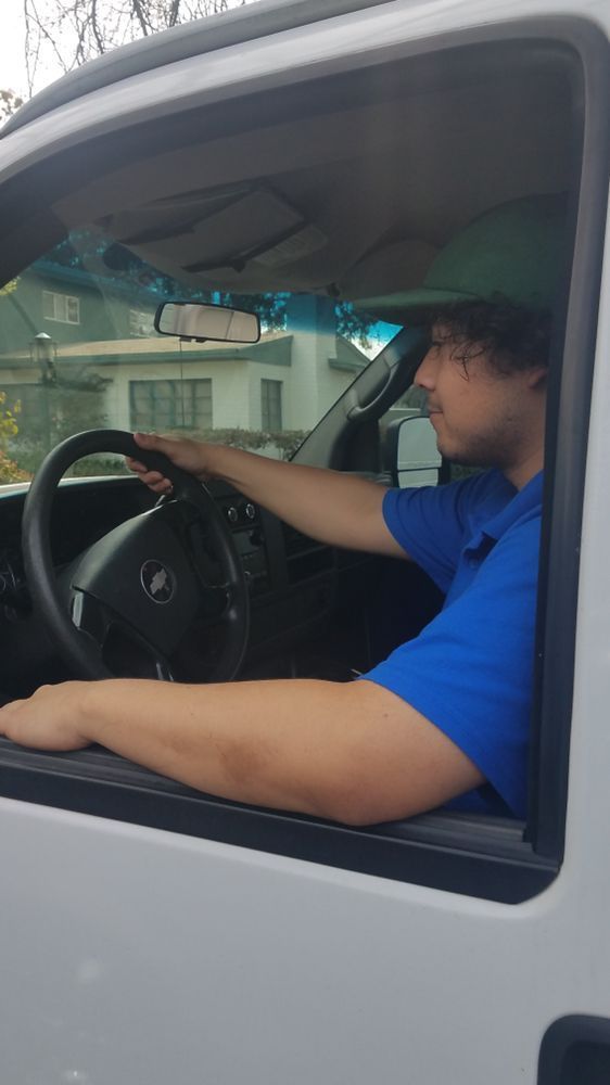 A man in a blue shirt is driving a white van