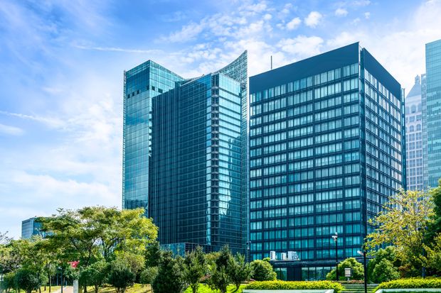 A group of tall buildings in a city with trees in the foreground.