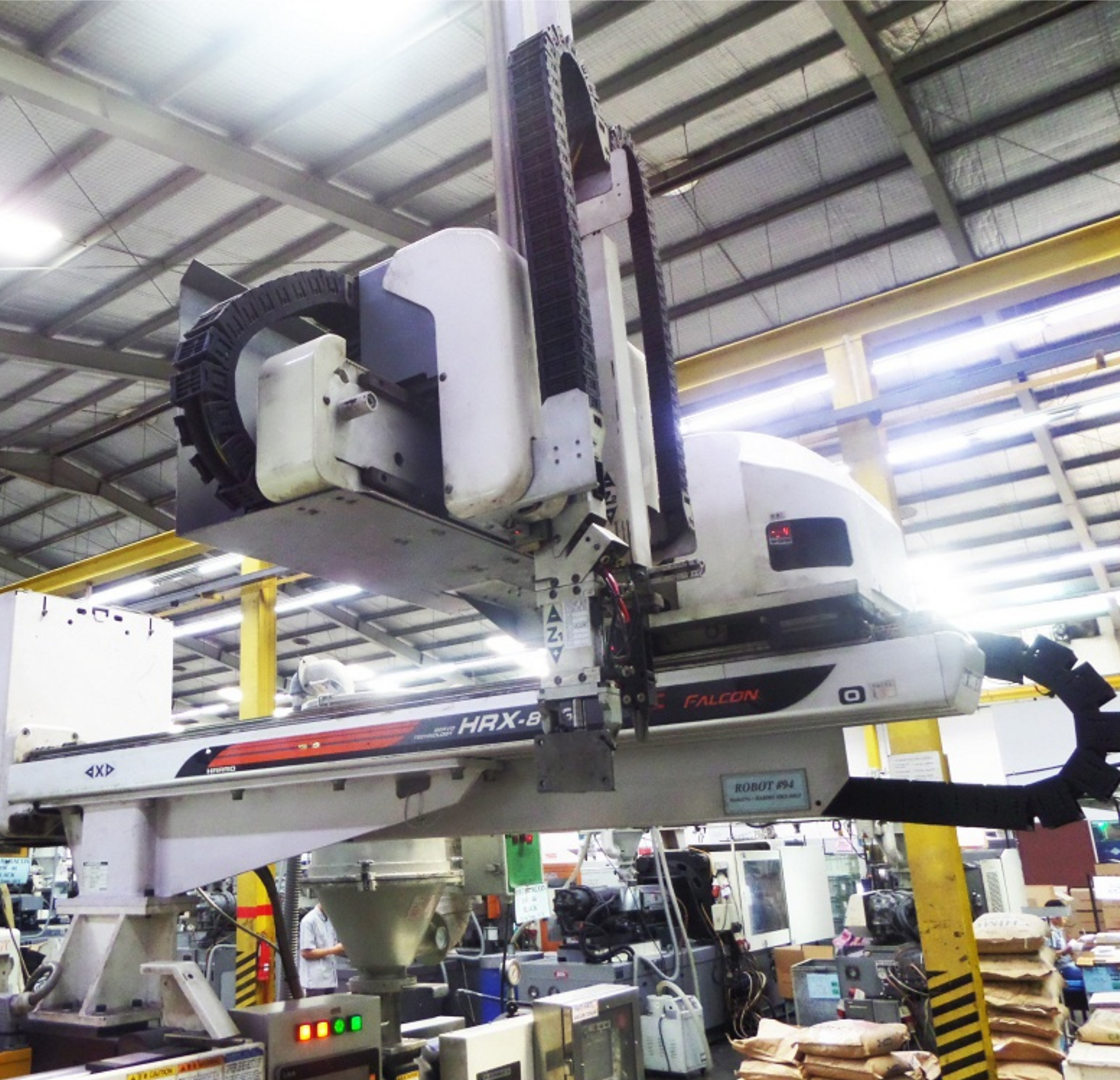 White robotic arm in a factory, picking up objects.