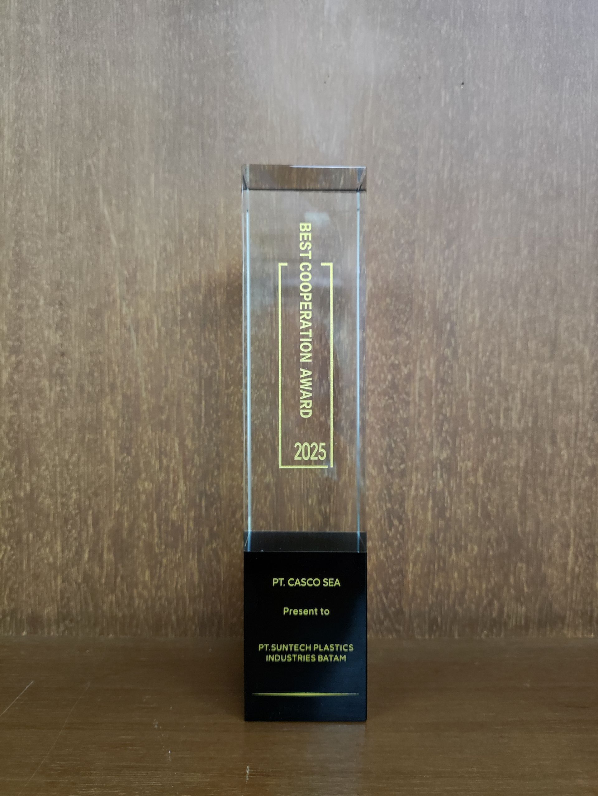 Trophy with "Best Corporation Awards" on clear acrylic column, wooden top, black base, text: "Air Canada 2023" against a wood background.