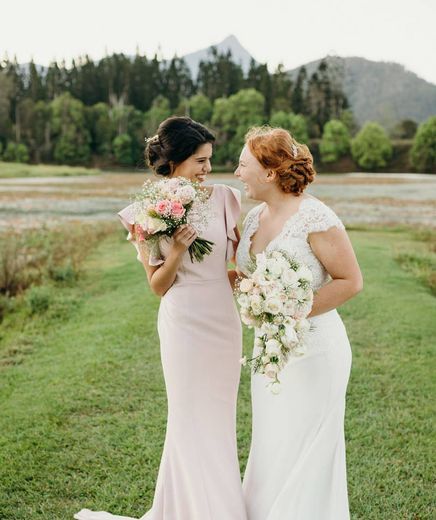 two brides holding flowers in a field