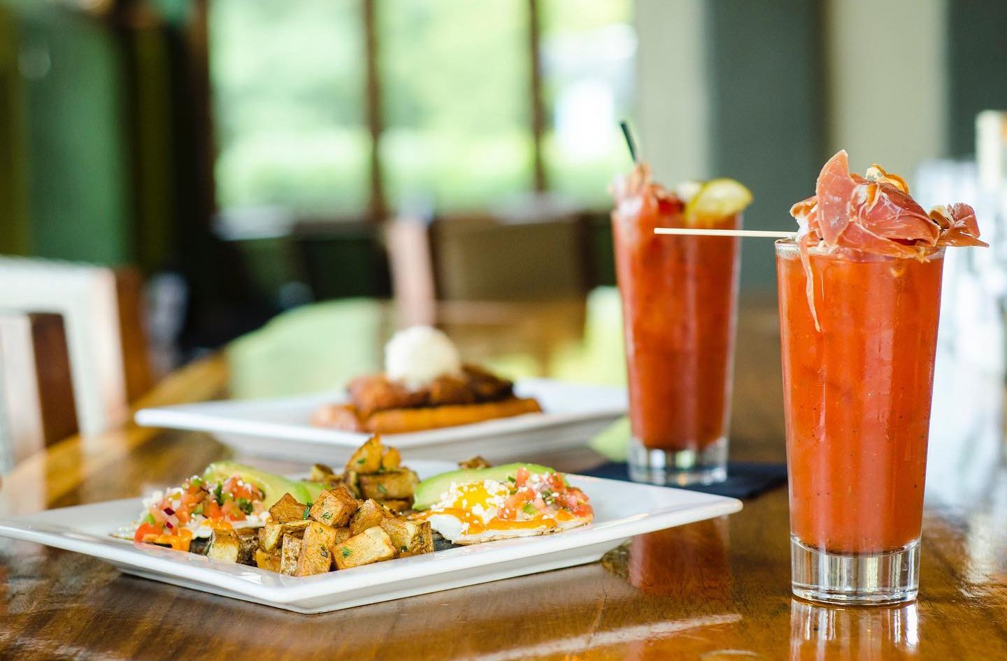 Brunch spread: Tomato cocktails with prosciutto, waffles, and a plate of potatoes and eggs.